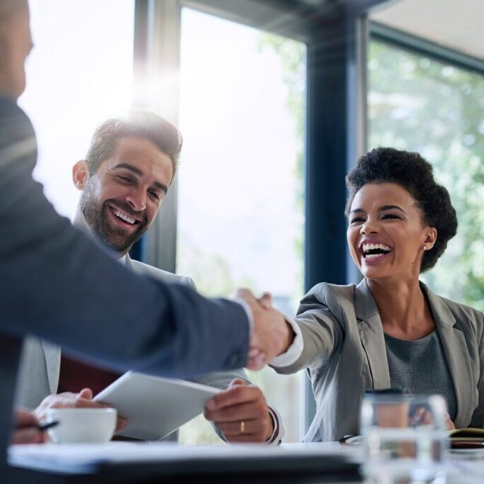 Meeting, partnership and business people shaking hands in the office for a deal, collaboration or onboarding. Diversity, professional and employees with handshake for agreement, welcome or greeting